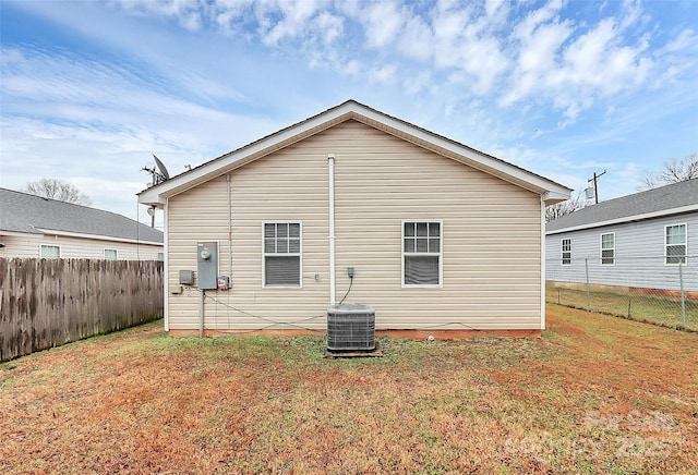 rear view of house with cooling unit and a yard