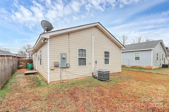 back of property featuring central AC unit and a yard