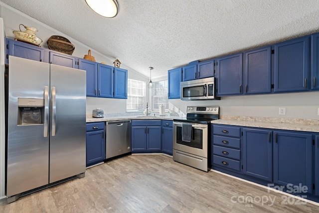 kitchen featuring sink, stainless steel appliances, blue cabinetry, and lofted ceiling