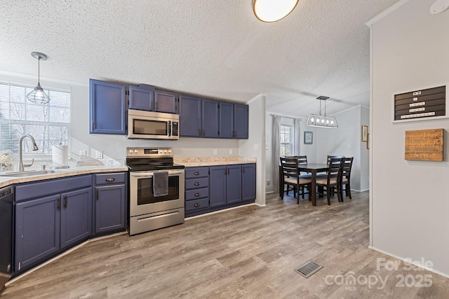 kitchen featuring appliances with stainless steel finishes, blue cabinetry, pendant lighting, and sink