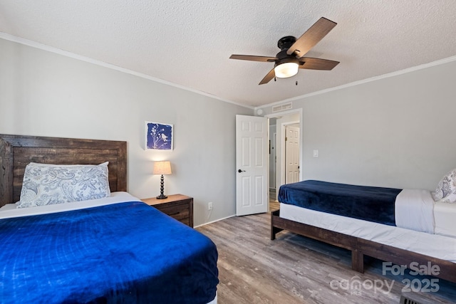 bedroom with a textured ceiling, ceiling fan, crown molding, and hardwood / wood-style floors