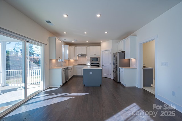 kitchen featuring white cabinetry, a kitchen island, dark wood-type flooring, and appliances with stainless steel finishes