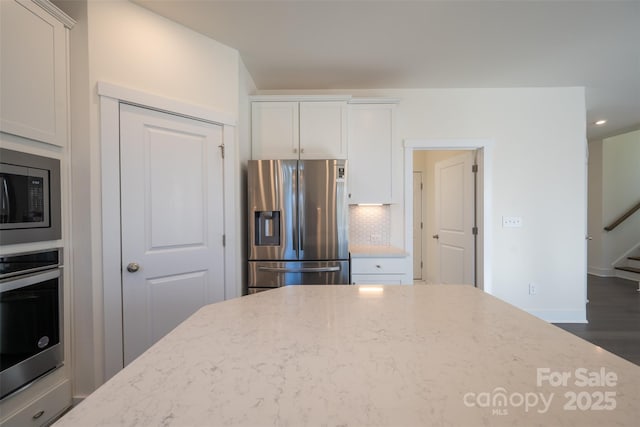 kitchen featuring dark wood-type flooring, decorative backsplash, light stone counters, white cabinetry, and stainless steel appliances