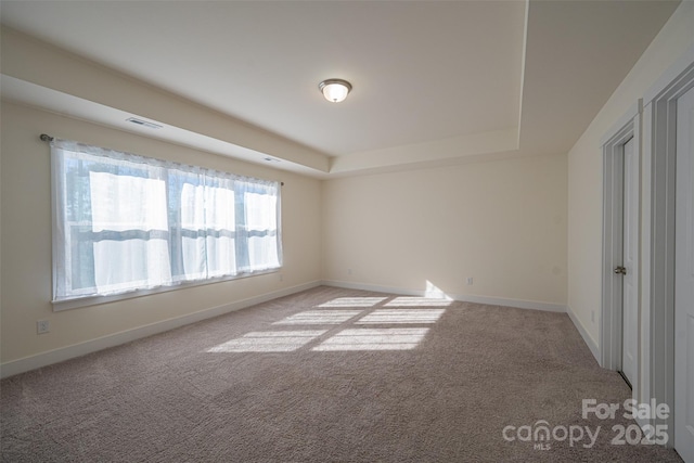 carpeted empty room with a tray ceiling