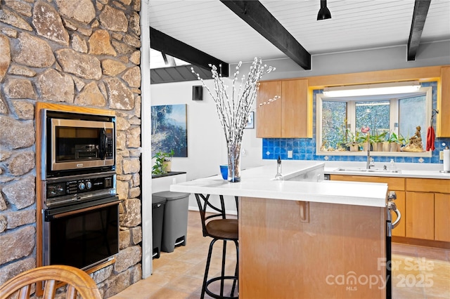 kitchen with backsplash, sink, beam ceiling, black oven, and stainless steel microwave