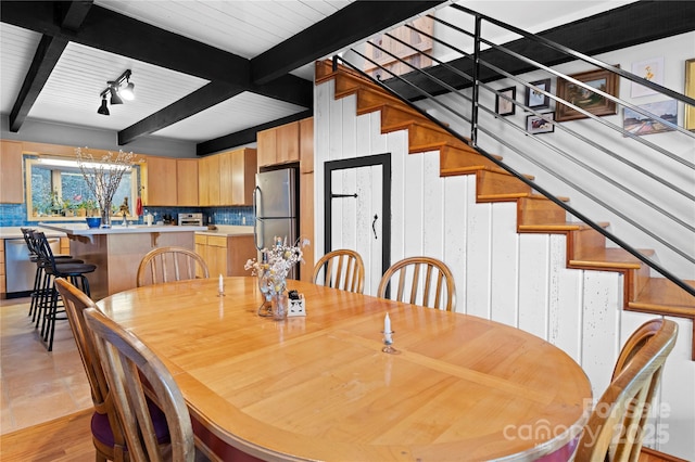 dining area featuring beam ceiling, wooden walls, and a notable chandelier