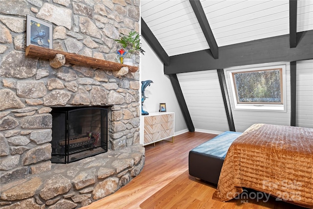 bedroom with hardwood / wood-style flooring, lofted ceiling with beams, and a fireplace