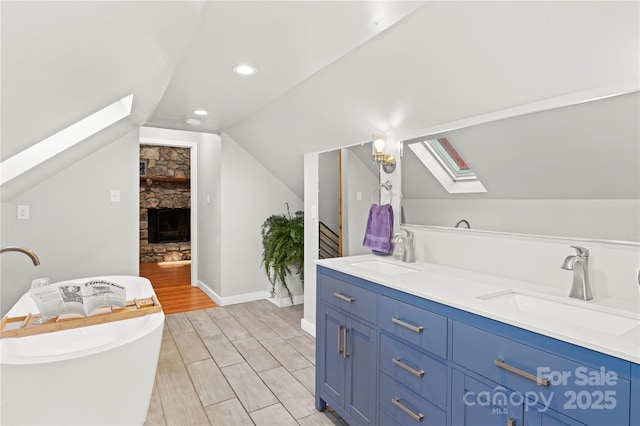 bathroom featuring a fireplace, vanity, and vaulted ceiling