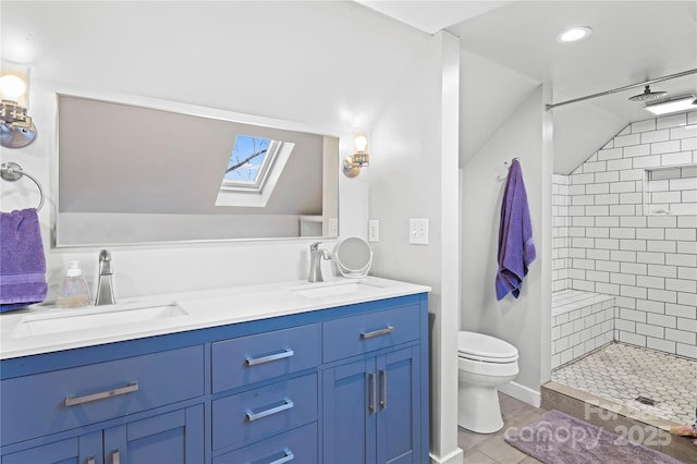 bathroom featuring tiled shower, vanity, a skylight, and toilet