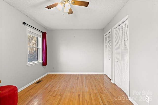 unfurnished bedroom with ceiling fan, a textured ceiling, and light hardwood / wood-style flooring