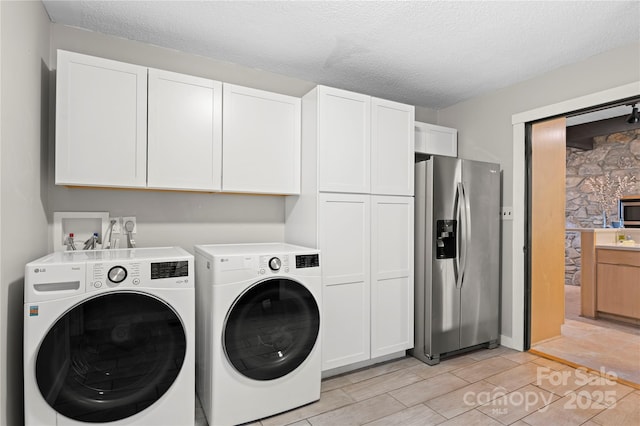 clothes washing area featuring cabinets, independent washer and dryer, and a textured ceiling