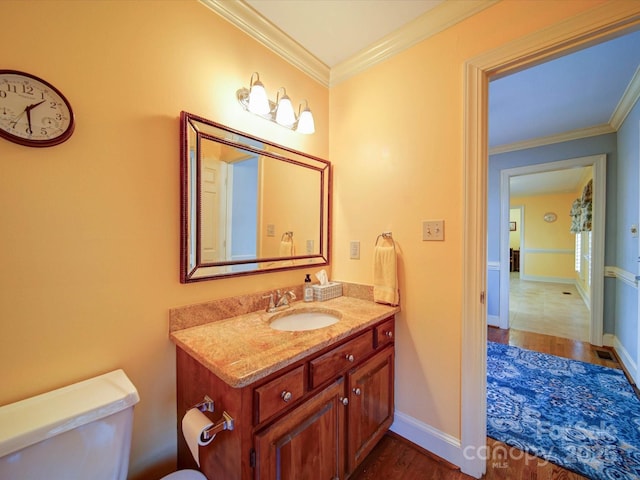 bathroom featuring toilet, hardwood / wood-style floors, vanity, and ornamental molding