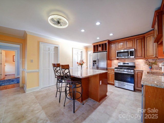 kitchen with a center island, sink, light stone countertops, and stainless steel appliances