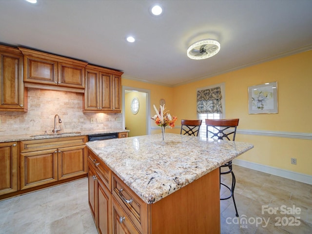 kitchen with sink, a center island, a kitchen breakfast bar, light stone counters, and crown molding