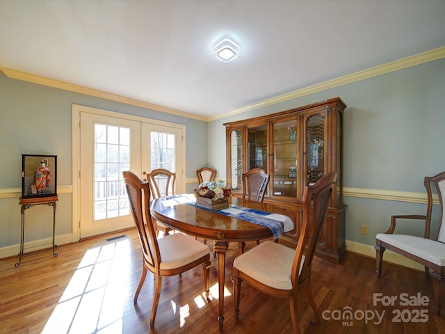 dining room with wood-type flooring, french doors, and crown molding