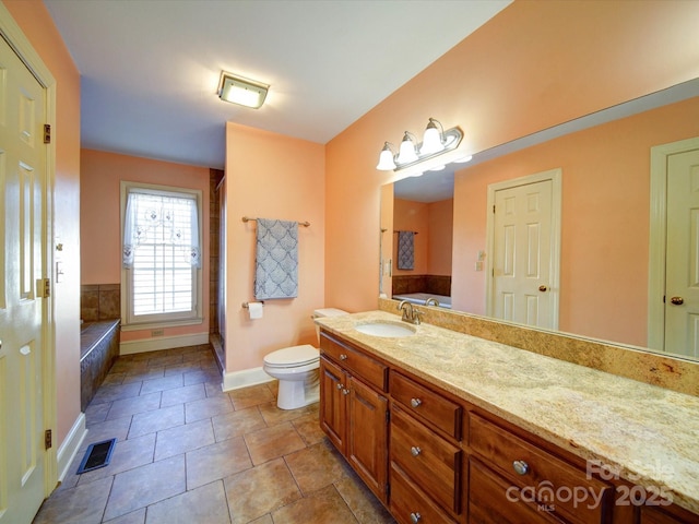 bathroom featuring tile patterned floors, tiled bath, vanity, and toilet