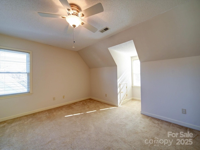 bonus room with ceiling fan, light colored carpet, a textured ceiling, and vaulted ceiling