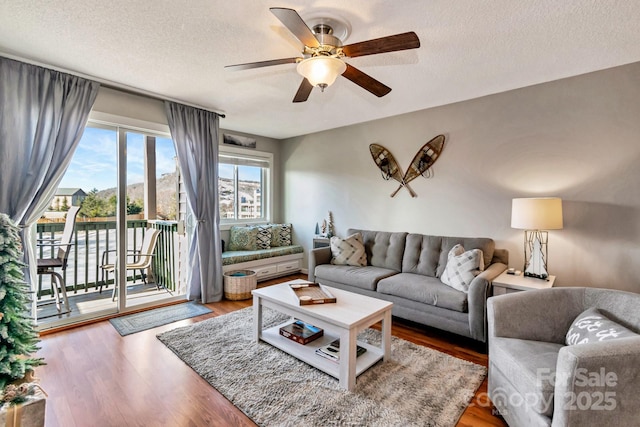 living room with wood-type flooring, a textured ceiling, and ceiling fan