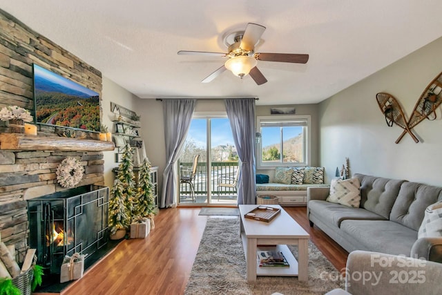 living room with a fireplace, hardwood / wood-style floors, a textured ceiling, and ceiling fan