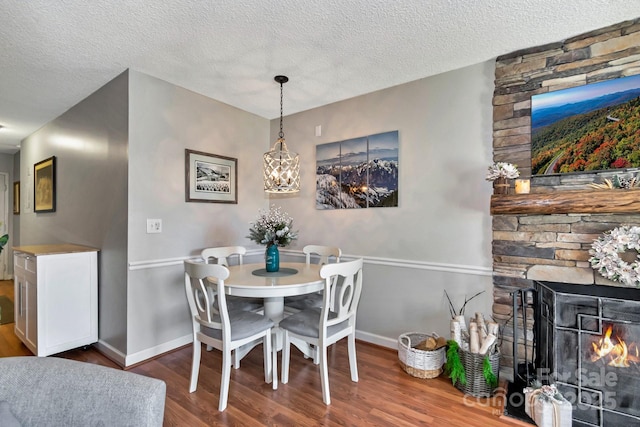 dining room with dark hardwood / wood-style flooring, a stone fireplace, and a textured ceiling