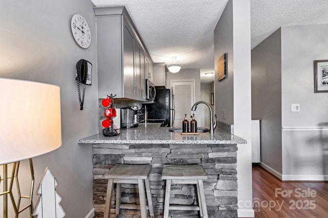 kitchen featuring gray cabinetry, sink, dark hardwood / wood-style floors, a textured ceiling, and light stone counters