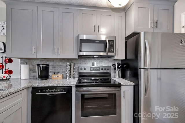 kitchen featuring decorative backsplash, light stone counters, and stainless steel appliances