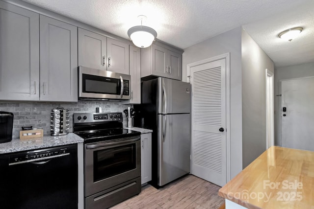 kitchen with decorative backsplash, appliances with stainless steel finishes, a textured ceiling, and gray cabinets