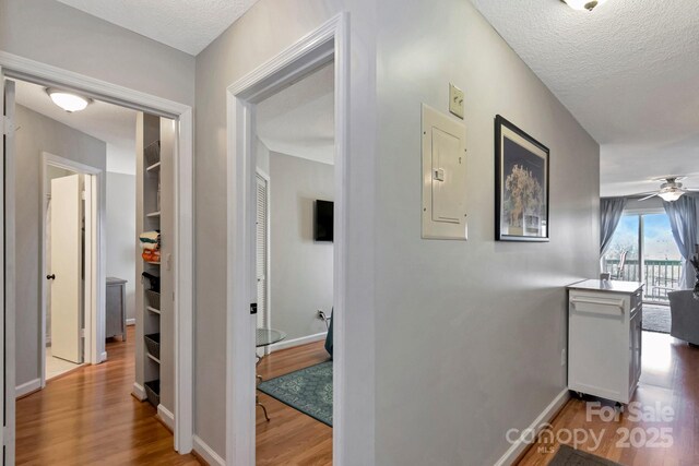 hall featuring wood-type flooring, a textured ceiling, and electric panel