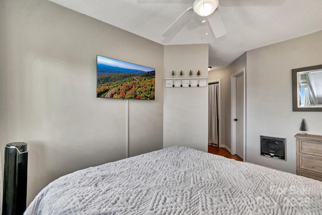 bedroom with ceiling fan, wood-type flooring, and a textured ceiling