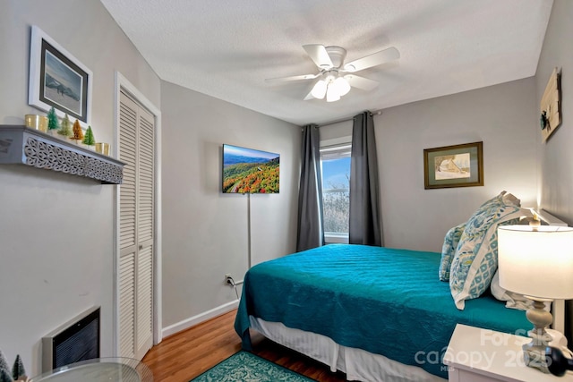 bedroom featuring wood-type flooring, a textured ceiling, a closet, and ceiling fan