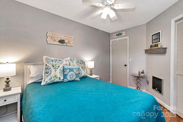 bedroom featuring heating unit, ceiling fan, a closet, and a textured ceiling