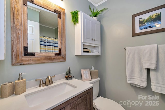 bathroom featuring vanity, toilet, and crown molding