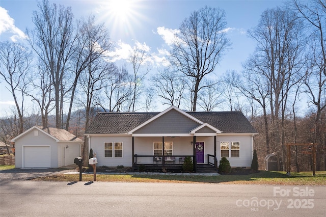 view of front of house with covered porch, a garage, and an outbuilding