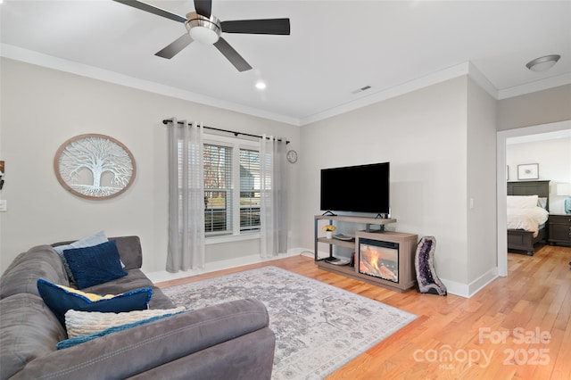 living room featuring hardwood / wood-style floors, ceiling fan, and ornamental molding