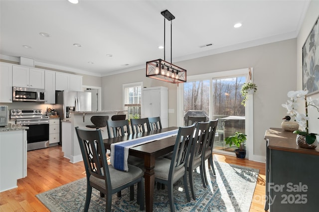 dining area with light hardwood / wood-style floors and crown molding