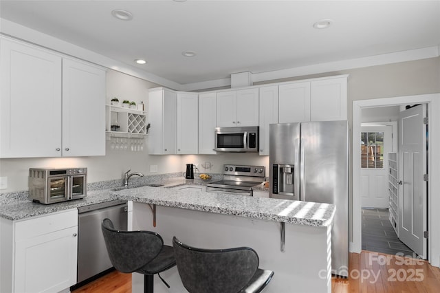 kitchen featuring white cabinetry, light stone countertops, light wood-type flooring, and appliances with stainless steel finishes