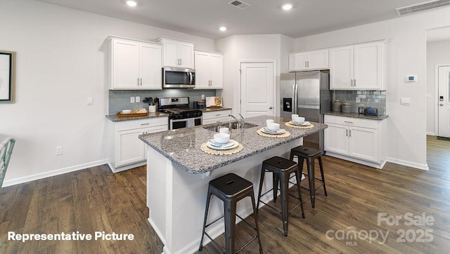 kitchen featuring stainless steel appliances, white cabinetry, a kitchen island with sink, and sink