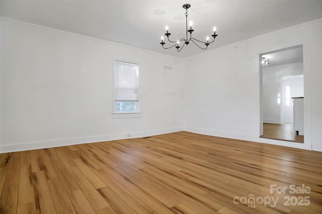 spare room with light wood-type flooring, ornamental molding, and a chandelier