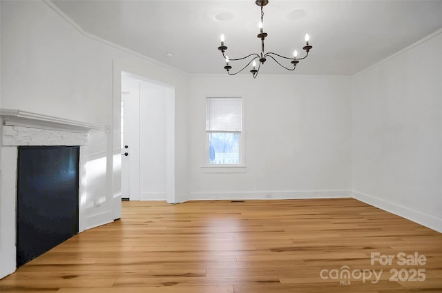 unfurnished dining area featuring crown molding, light hardwood / wood-style flooring, and a chandelier