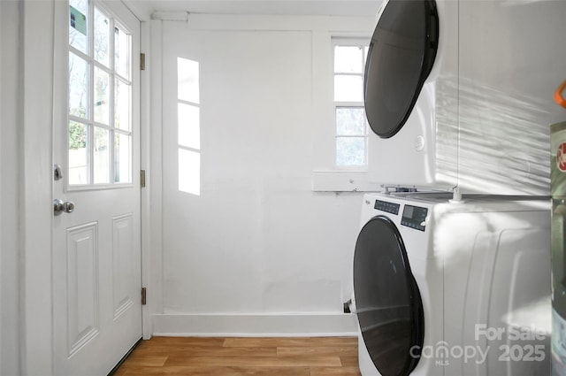 washroom with stacked washer and dryer and light hardwood / wood-style floors