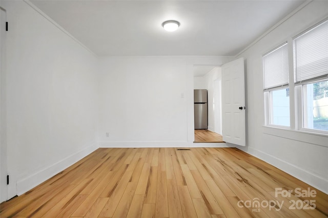 empty room with light hardwood / wood-style floors and ornamental molding