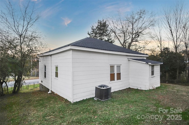 property exterior at dusk with central air condition unit and a lawn