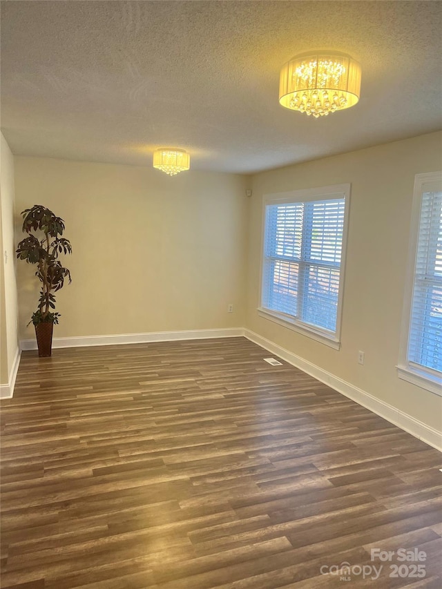 empty room with a textured ceiling and dark hardwood / wood-style floors