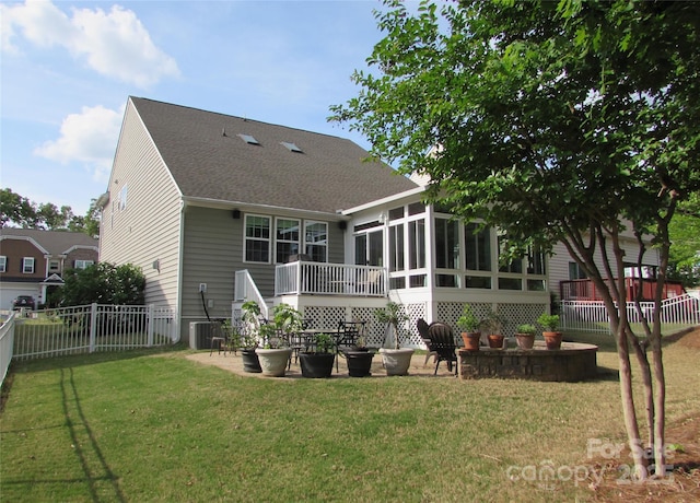 rear view of property with cooling unit, a fenced backyard, a sunroom, a shingled roof, and a yard