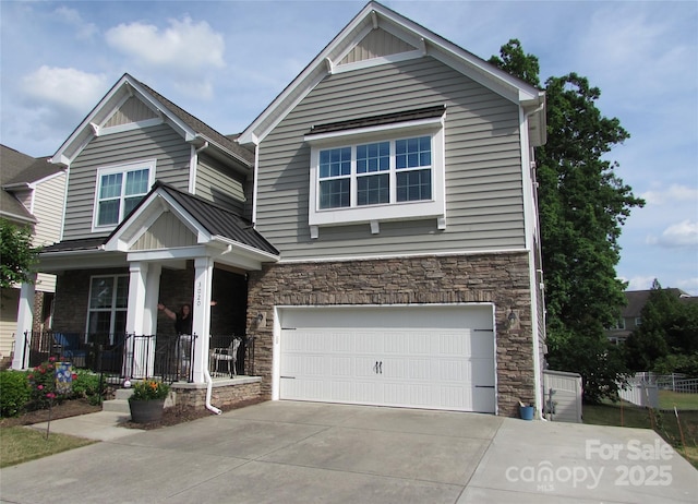 craftsman-style house with stone siding, a garage, covered porch, driveway, and metal roof