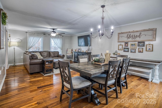 dining room featuring wood-type flooring, ceiling fan with notable chandelier, and crown molding