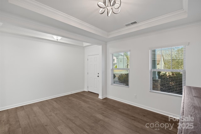 spare room with a tray ceiling, a chandelier, dark hardwood / wood-style floors, and ornamental molding