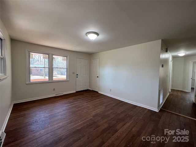 spare room with visible vents, dark wood finished floors, and baseboards