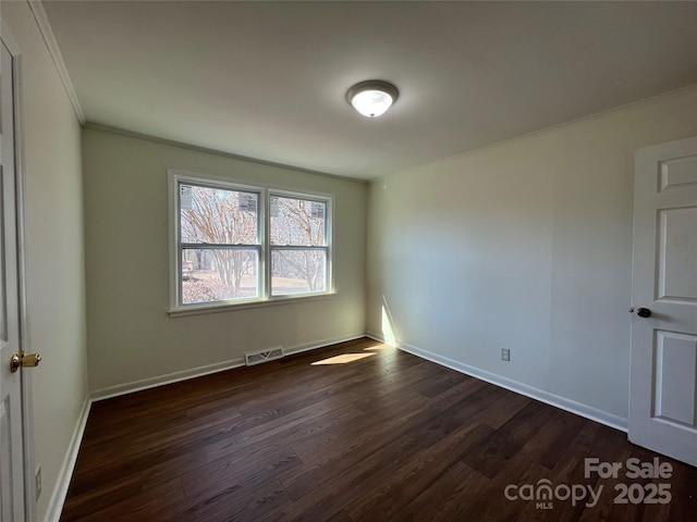 spare room with ornamental molding, dark wood-style flooring, visible vents, and baseboards