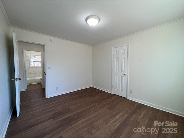 spare room featuring crown molding, dark wood finished floors, and baseboards